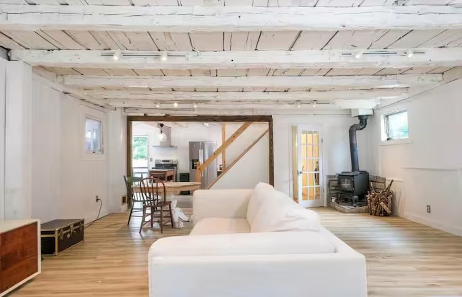 Un vaste espace de vie doté d’un canapé blanc, de parquet et d’un escalier menant à un niveau supérieur.