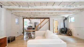 Un vaste espace de vie doté d’un canapé blanc, de parquet et d’un escalier menant à un niveau supérieur.