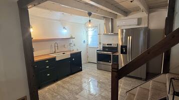 A modern kitchen with a central island, stainless steel appliances, and a wooden staircase.