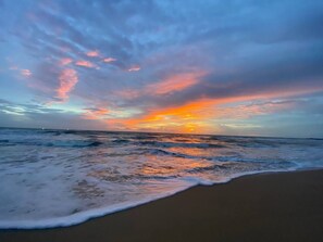Une plage avec des vagues et un coucher de soleil.