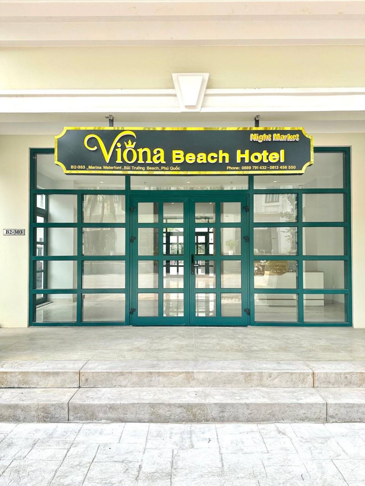 The entrance to Viona Beach Hotel with a signboard displaying the hotel's name and contact information.