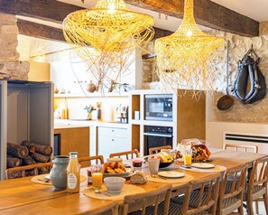 A rustic dining area with a wooden table set for breakfast, featuring a bottle of juice, bread, and a bowl of fruit. - Vrbo Property (Sault)