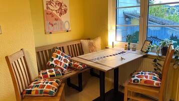 Ein Zimmer mit einer Holzbank, einem Tisch und Stühlen mit bunten Kissen.