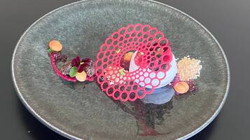 A round plate with a central pink decorative element, surrounded by various food items and garnishes.