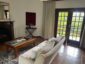 A living room with a sofa, a coffee table, a fireplace, a mirror, and a view through a door. - Secluded Chalet Retreat Near Kruger Park, Luxury Meets Nature, Farm Living (Mbombela)