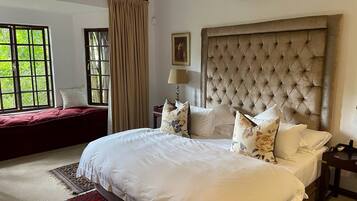 Une chambre d’hôtel avec un grand lit, une fenêtre avec des rideaux, une table de chevet avec une lampe et un appareil de climatisation.
