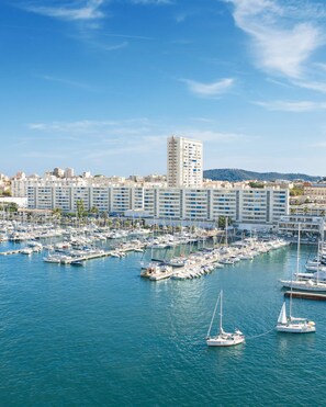 Un puerto deportivo con numerosas embarcaciones amarradas, rodeado por un paisaje urbano con edificios modernos.