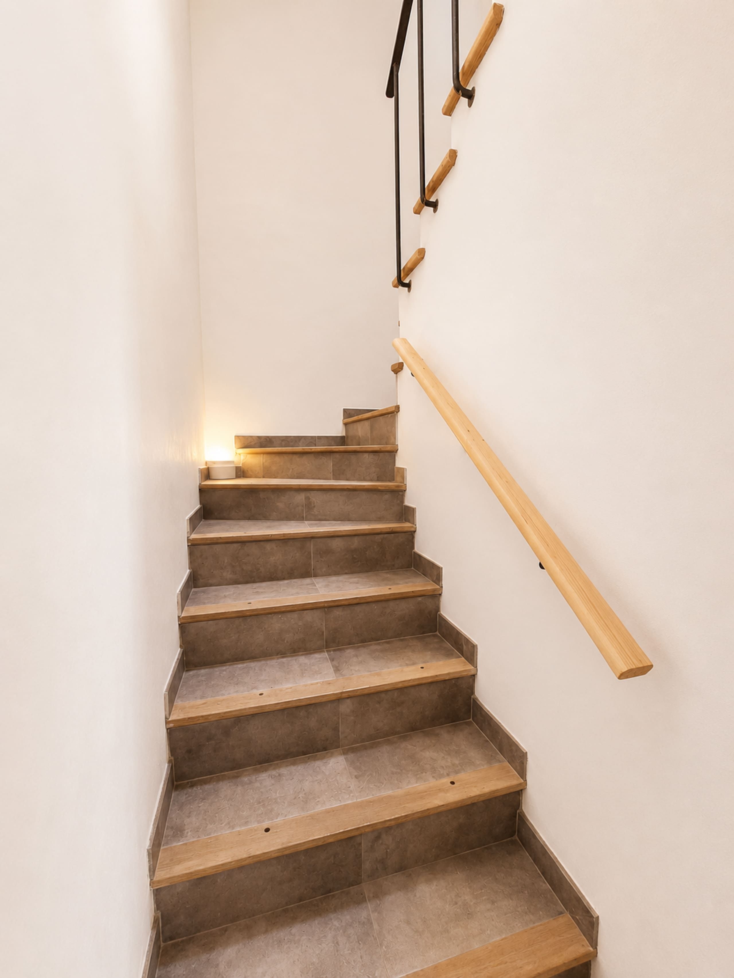 A staircase with wooden steps and handrails, leading upwards.
