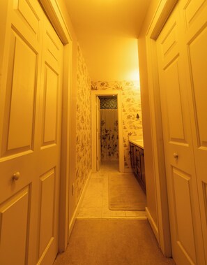 A hallway with white doors and patterned wallpaper, leading to a bathroom with a shower and a sink. - Cozy 4-bedroom house in tranquil Beech Mountain with AC And Hot Tub. (Beech Mountain)