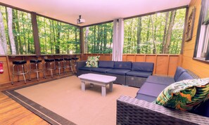 Ein geräumiges Zimmer mit großem Fenster, einer Couch, einem Couchtisch und einer Bar mit Hockern.