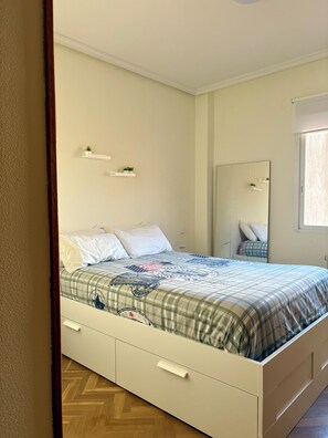 A bedroom with a bed, a mirror, and a window. - Vrbo Property (Unknown)