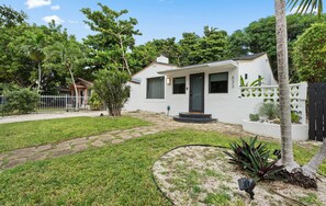 A single-story house with a white exterior, a front porch, and a paved driveway. - Our Miami House - Cozy 3BR Near Design District & Wynwood (Miami)