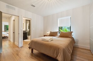 A modern bedroom with a large bed, a walk-in closet, and a bathroom with a glass shower. - Our Miami House - Cozy 3BR Near Design District & Wynwood (Miami)