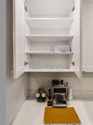 A kitchen with white cabinets, a coffee machine, and a spice rack. - Our Miami House - Cozy 3BR Near Design District & Wynwood (Miami)