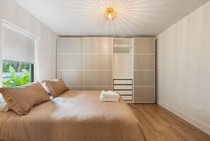 A bedroom with a bed, a closet, and a window with a view of greenery. - Our Miami House - Cozy 3BR Near Design District & Wynwood (Miami)