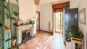 A room with a fireplace, a radiator, a wooden door, and a view of the outside.