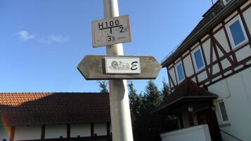 Ein Wegweiser mit mehreren Schildern, darunter eines mit der Aufschrift 'H100' und ein weiteres mit einem Symbol und dem Buchstaben 'E'.