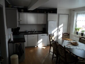 Une cuisine compacte avec des meubles blancs, un évier et une table à manger avec des chaises.