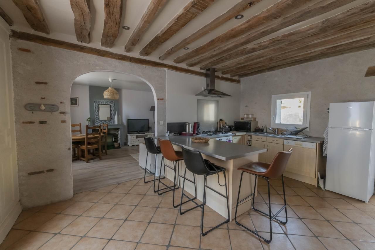 Une cuisine spacieuse avec un îlot central, des tabourets de bar et une grande fenêtre.