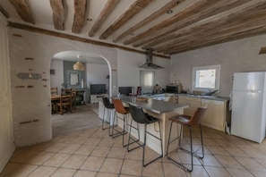 Een ruime keuken met een centraal eiland, barstoelen en een groot raam.