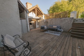 Een houten terras met buitenmeubilair, een stenen muur en een houten omheining.