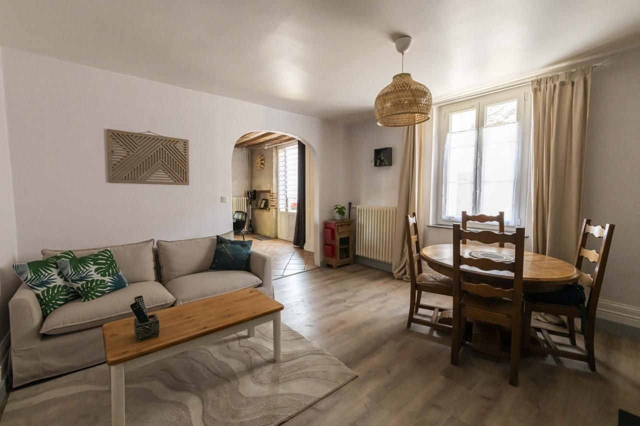 Un salon comprenant un canapé, une table basse en bois et un coin repas avec une table et des chaises.