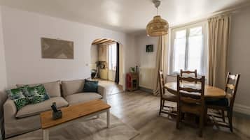 Un salon comprenant un canapé, une table basse en bois et un coin repas avec une table et des chaises.