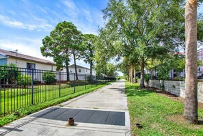 Una calle residencial con casas, aceras y una valla de metal.