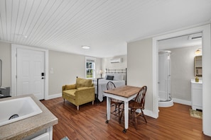 A room with a bed, a table, a chair, a sofa, a bathroom, and a sink. - Charming Mount Dora Studio Cottage (Mount Dora)