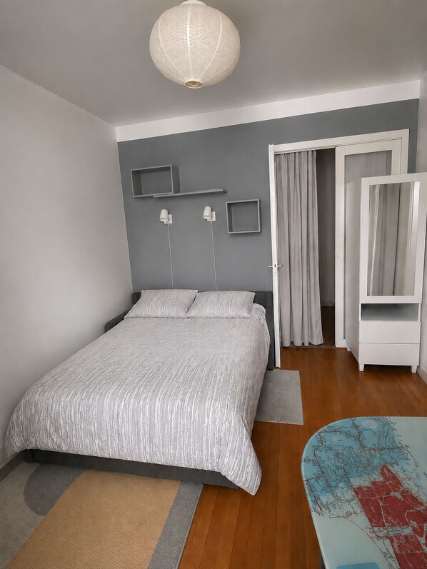 A bedroom with a bed, a wardrobe, a map on the floor, and a hanging light fixture. - Vrbo Property (Paris)