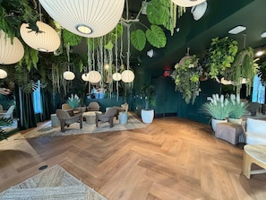 A room with wooden flooring, hanging plants, and a seating area with chairs and a table. - NEW   High-Rise 1BR Den  Rooftop Pool   Gym 402 (Miami)