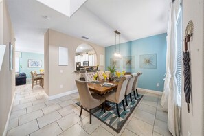 A dining area with a wooden table and chairs, a kitchen in the background, and a ceiling with recessed lighting. - COMING SOON   Solterra 5184 (Davenport)