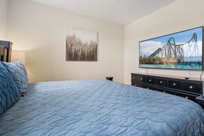A bedroom with a large bed, a flat-screen TV mounted on the wall, a nightstand, and a dresser. - NEW   3BR Private Pool  Mickey Room   Air Hockey (Four Corners)