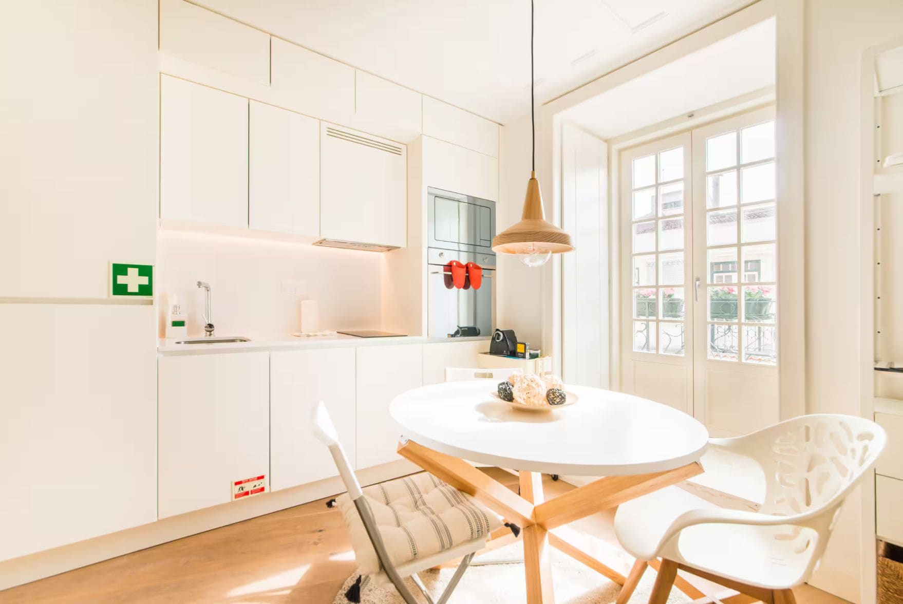 Een moderne keuken met witte kasten, een ronde eettafel en een hangende hanglamp.