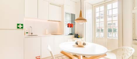 A modern kitchen with white cabinets, a round dining table, and a hanging pendant light.