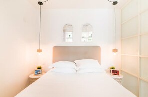 Ein Schlafzimmer mit einem großen Bett, zwei Nachttischen und zwei Wandleuchten.