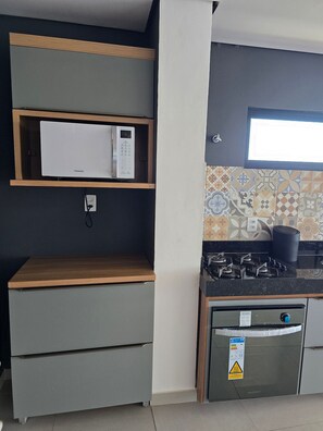 A compact kitchen with a microwave, stove, and built-in oven. - MB I - Ap. 405 - Nico Uruguay (Ipojuca)