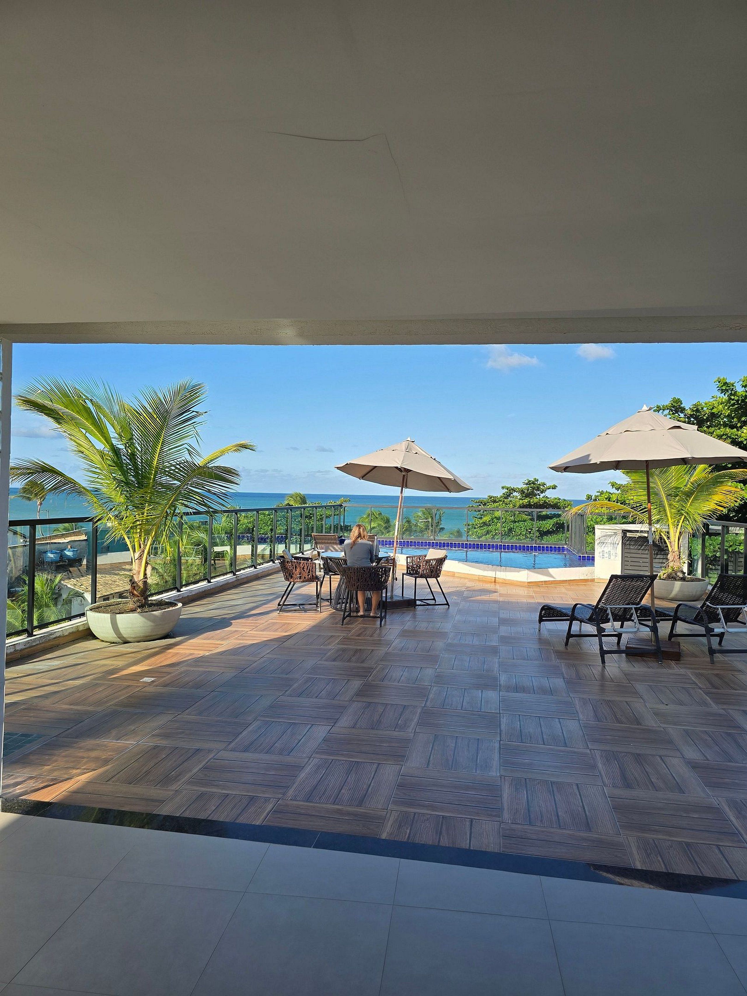 Une terrasse avec une piscine, des chaises longues et des parasols.