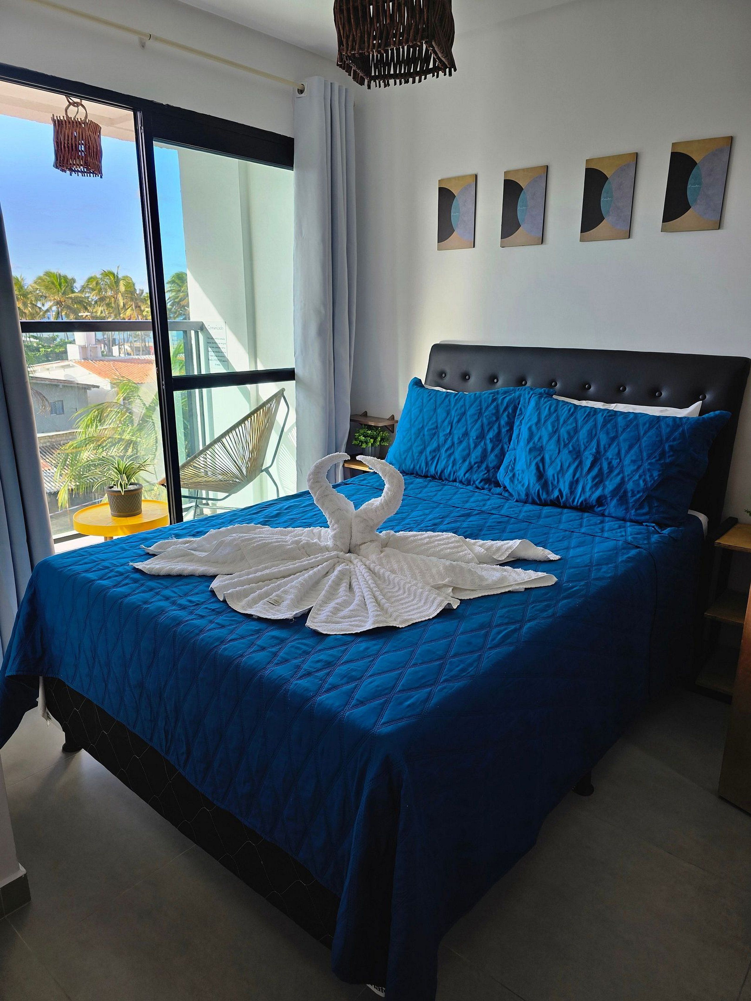 Una habitación de hotel moderna con una cama grande, un balcón y vistas a palmeras.