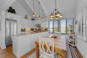 A kitchen with white cabinetry, a wooden island, and pendant lighting. - Seabrook Exclusives | 912 Sealoft (Seabrook Island)