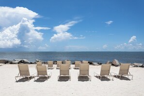 Een strand met rijen beige ligbedden gericht op de oceaan.
