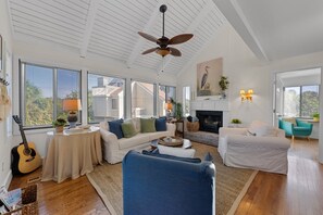 A spacious living room with a high ceiling, a fireplace, and large windows. - Seabrook Exclusives | 912 Sealoft (Seabrook Island)