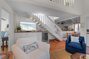 A spacious living area with a white staircase, a kitchen, and a dining area. - Seabrook Exclusives | 912 Sealoft (Seabrook Island)