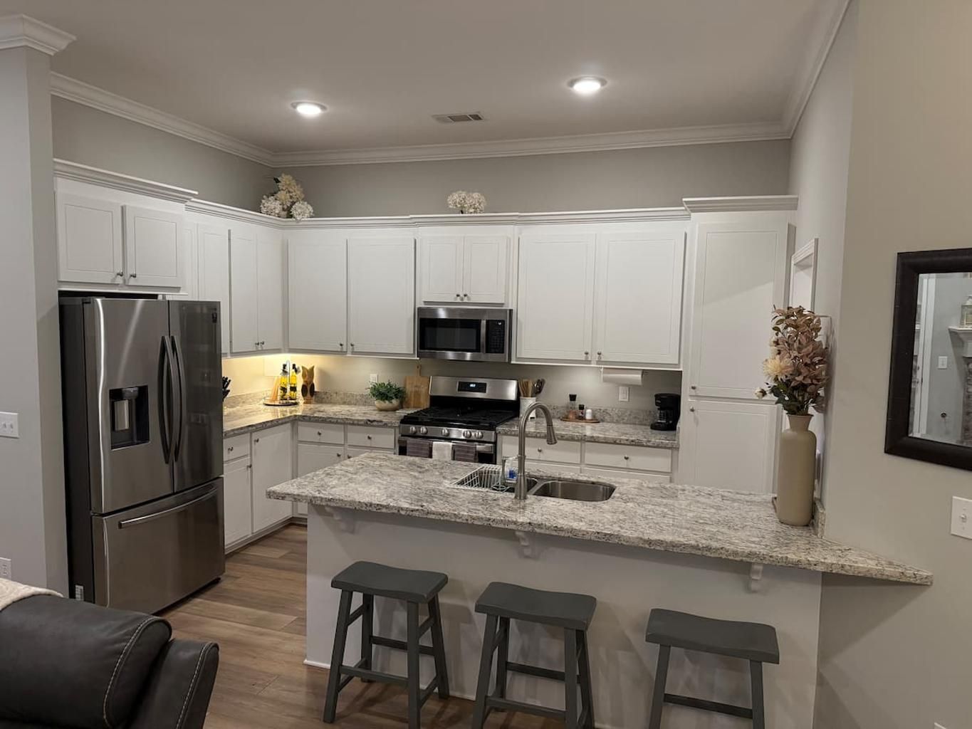 A modern kitchen with white cabinetry, stainless steel appliances, and a granite countertop.