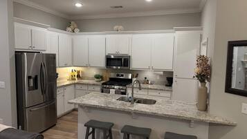 A modern kitchen with white cabinetry, stainless steel appliances, and a granite countertop.