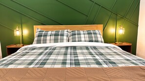 Ein Bett mit karierter Bettdecke, einem Holz-Kopfschild und zwei Nachttischlampen.