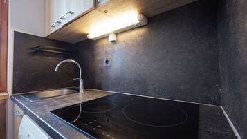 A kitchen with a black countertop, stainless steel sink, and a built-in electric stove.