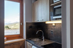A compact kitchen with a window, a sink, and a built-in oven. - Creux de l'Ours (Les Allues)