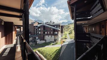 A hotel with a view of a mountainous landscape, featuring a stone facade and wooden balconies.