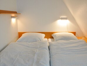 A twin room with two beds, each with a pillow and a headboard. - Karoline House Apartment Lise (Utersum)
